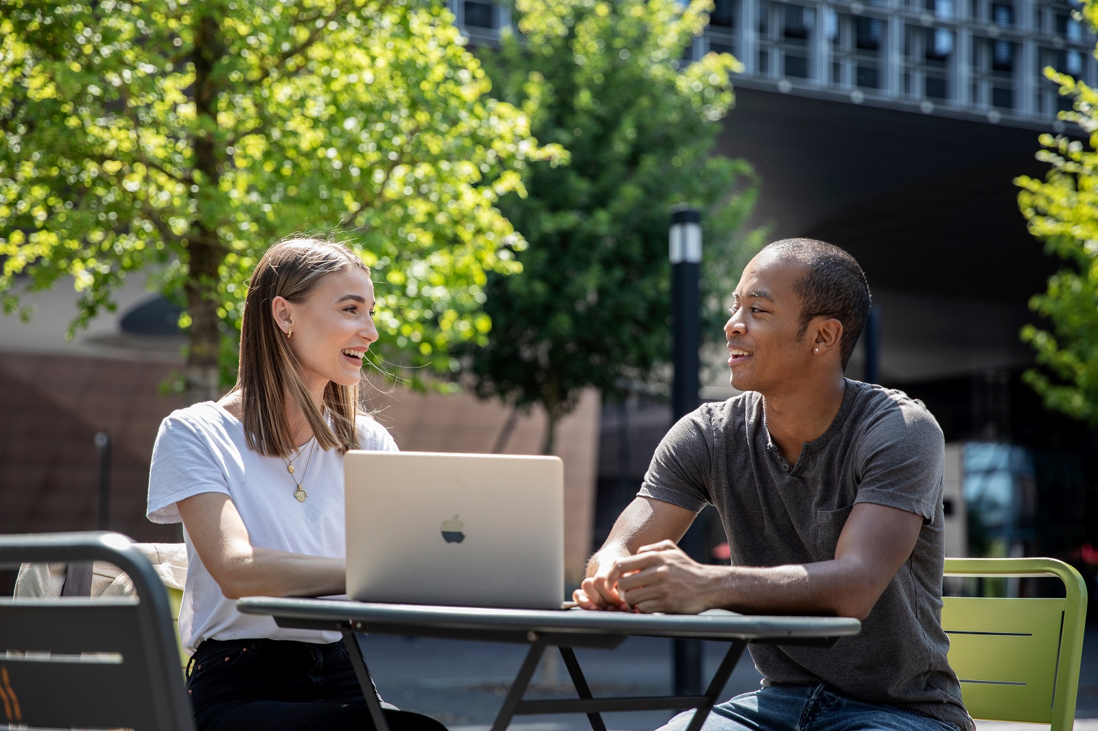 Two students sitting outside Maison du Savoir